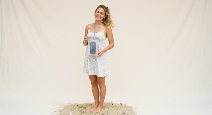 A beachgoer keeps their phone safe in a waterproof pouch at the shore.